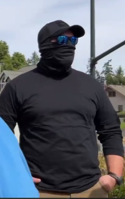Erick with his face covered by a black gaiter, blue sunglasses and black hat