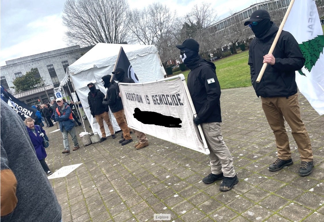 RCN members hold a banner reading 'Abortion is Genocide' while Dorsey holds an 'Appeal to Heaven' flag.